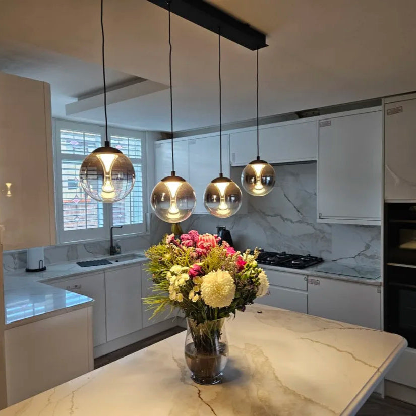 Modern kitchen with pendant lights and a vase of flowers on the counter.