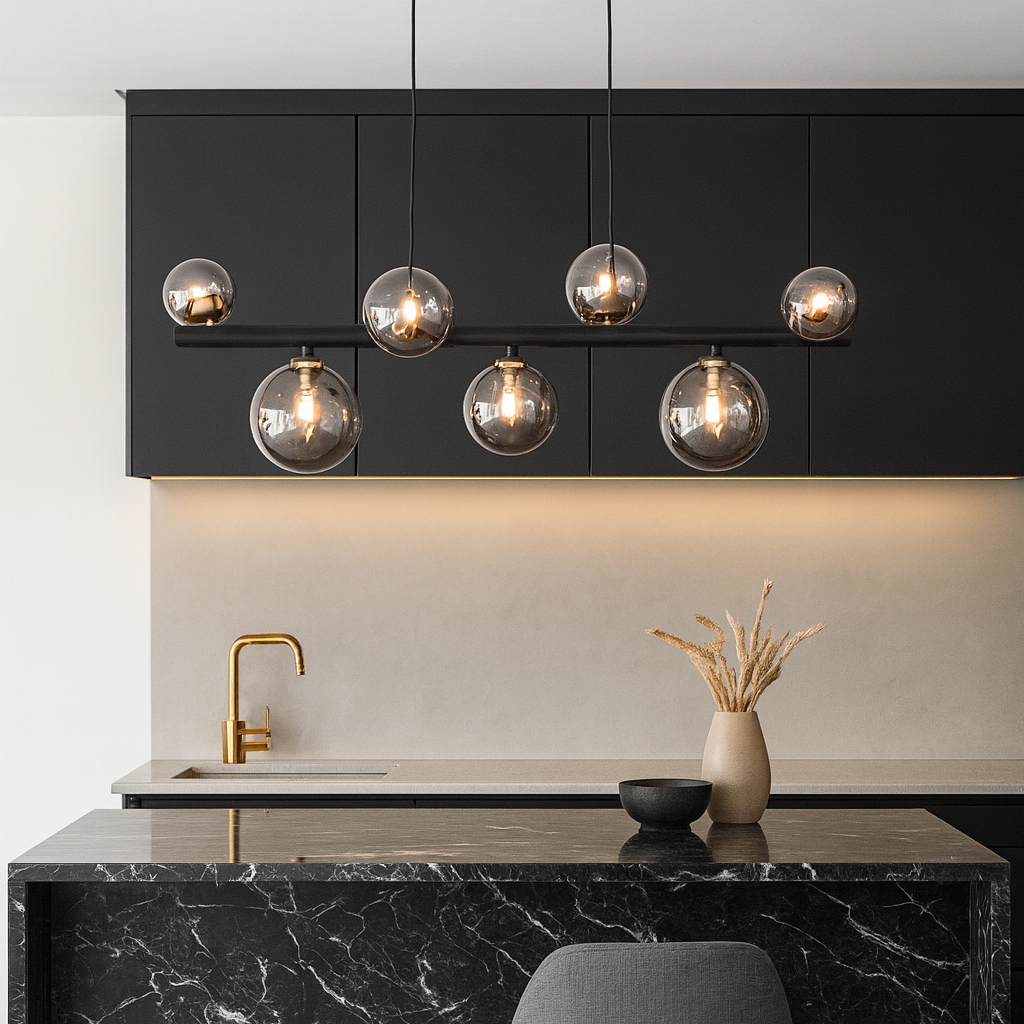 Marlow 6 light pendant bar in black and gold with smoked glass globes, 70cm wide, styled in a modern kitchen with black cabinets, gold tap, and marble island lighting.