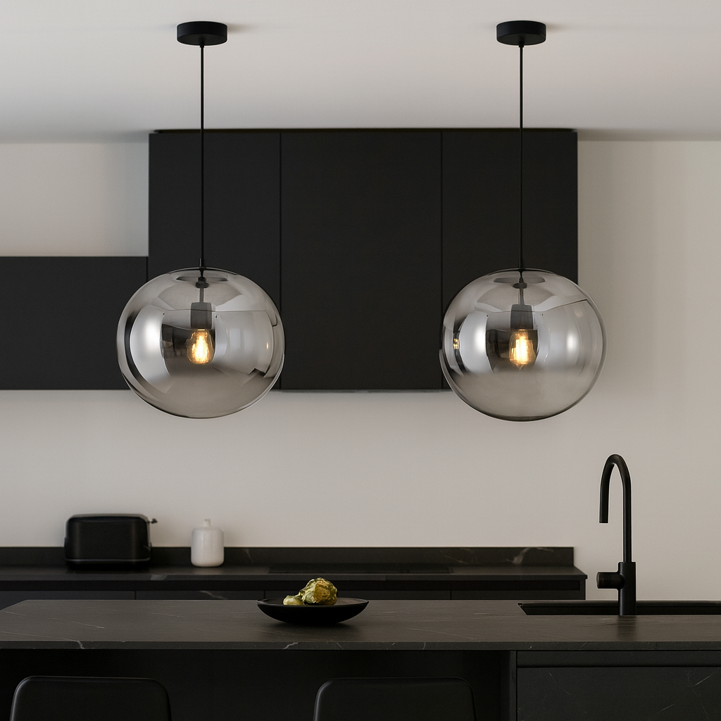 Modern kitchen with two smoked glass pendant lights hanging over a black island with black highlights.