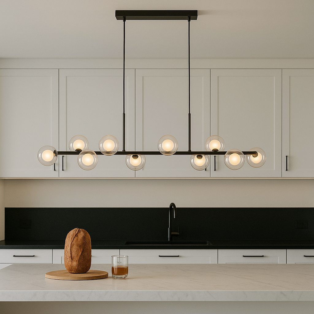Modern kitchen with white cabinets and black handles, featuring a 115cm pendant bar light with glass globe shades hanging above a marble island.